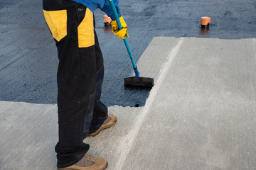 Worker applies bitumen mastic on the foundation