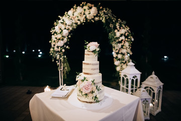 beautiful wedding cake with candles and flowers outdoors