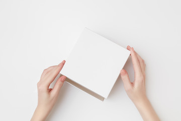 Mock up of white present box in women's hands on the white background