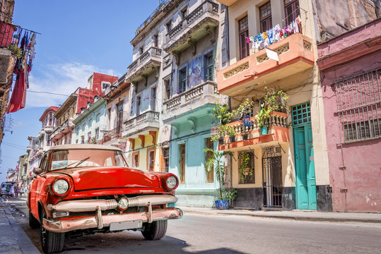 Vintage classic red american car in a colorful street of Havana, Cuba.