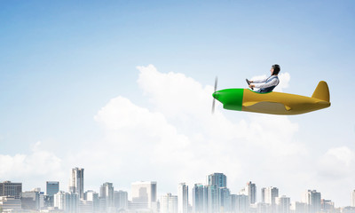 Businessman driving propeller plane above downtown