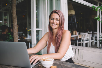 Confident modern woman working on laptop on street terrace