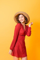 Powerful girl in red dress wearing hat posing relax in orange background