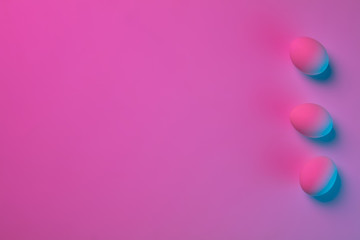 Egg hunt is coming. Easter traditions, pink-blue colored eggs on pink background, neon light, top view, copyspace for ad. Concept of holidays, spring, celebrating, food and sweets, family time.