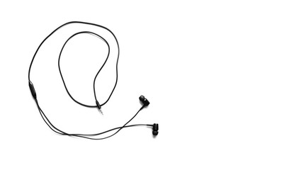 Black earphones lying on the white background. Modern music concept. Audio technology.