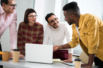 International group of young business people working and communicating standing near office desk.