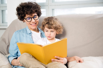 Happy woman and young boy reading a book