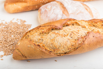 Different kinds of fresh baked bread on a white wooden background. side view.