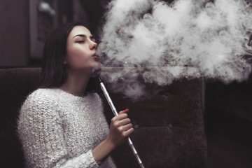 Fototapeta premium girl smokes a hookah, exhales smoke, a lot of smoke