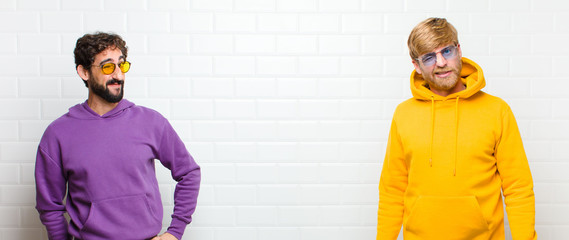 young cool men looking happy and friendly, smiling and winking an eye at you with a positive...
