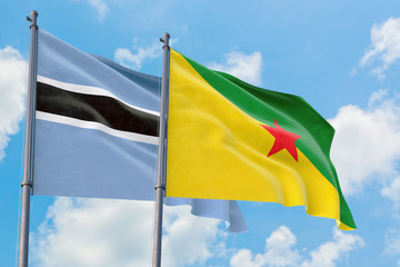 French Guiana and Botswana flags waving in the wind against white cloudy blue sky together. Diplomacy concept, international relations.