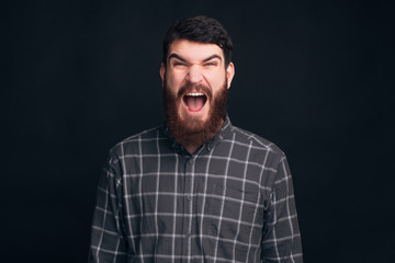Fototapeta premium Bearded man is screaming at the camera on dark background.