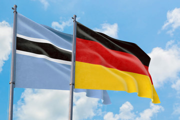 Germany and Botswana flags waving in the wind against white cloudy blue sky together. Diplomacy concept, international relations.