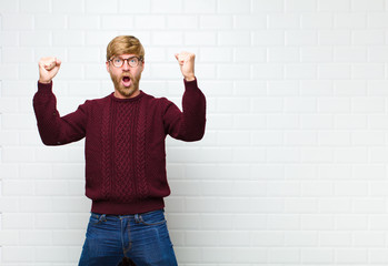 young blonde man celebrating an unbelievable success like a winner, looking excited and happy...