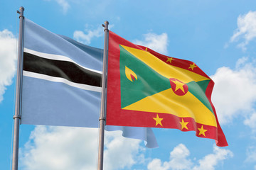 Grenada and Botswana flags waving in the wind against white cloudy blue sky together. Diplomacy concept, international relations.