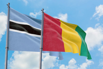 Guinea and Botswana flags waving in the wind against white cloudy blue sky together. Diplomacy concept, international relations.