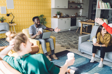 Cheerful multiethnic friends with drinks at home