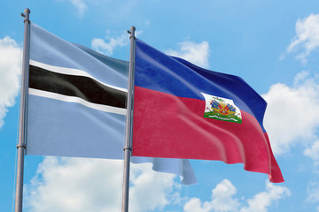 Haiti and Botswana flags waving in the wind against white cloudy blue sky together. Diplomacy concept, international relations.