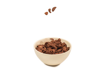 Chocolate corn flakes falling to the white bowl isolated on white. Motion.