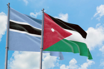 Jordan and Botswana flags waving in the wind against white cloudy blue sky together. Diplomacy concept, international relations.