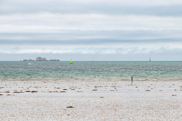 France. Bretagne. Une fille sur une plage de Saint Malo regarde le Grand Bé sur son ilôt sous un...
