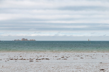 France. Bretagne. Une plage de Saint Malo et le Grand Bé sur son ilôt sous un ciel couvert.