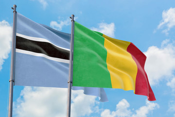 Mali and Botswana flags waving in the wind against white cloudy blue sky together. Diplomacy concept, international relations.