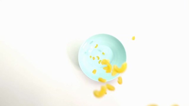 macaroni falls on a blue plate top view. close-up, slow-motion.