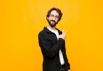 young crazy handsome man feeling happy, positive and successful, with hand making v shape over...