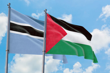 Palestine and Botswana flags waving in the wind against white cloudy blue sky together. Diplomacy concept, international relations.