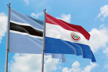 Paraguay and Botswana flags waving in the wind against white cloudy blue sky together. Diplomacy concept, international relations.