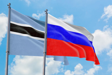 Russia and Botswana flags waving in the wind against white cloudy blue sky together. Diplomacy concept, international relations.