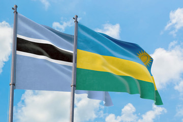 Rwanda and Botswana flags waving in the wind against white cloudy blue sky together. Diplomacy concept, international relations.