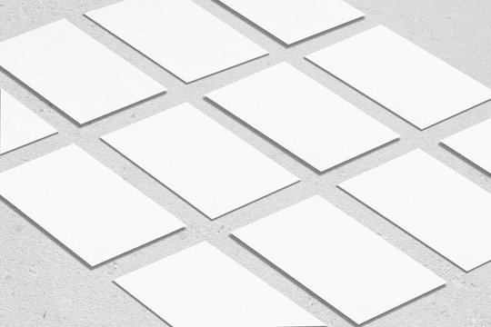 Closeup of empty white rectangle business card mockups lying diagonally on neutral grey concrete background. Flat lay, isometric view. Open composition. Blank Template for Corporate Identity