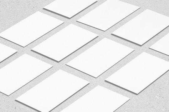 Closeup of empty white rectangle business card mockups lying diagonally on neutral grey concrete background. Flat lay, isometric view. Open composition. Blank Template for Corporate Identity