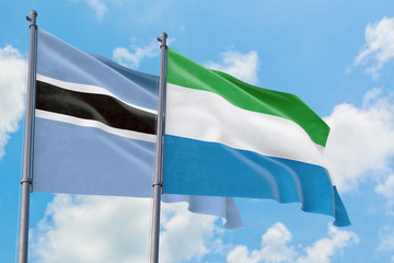 Sierra Leone and Botswana flags waving in the wind against white cloudy blue sky together. Diplomacy concept, international relations.