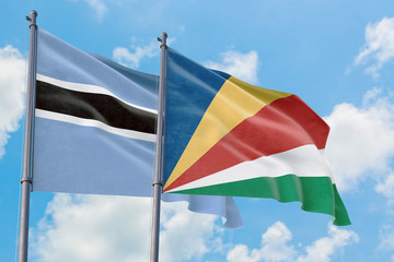 Seychelles and Botswana flags waving in the wind against white cloudy blue sky together. Diplomacy concept, international relations.