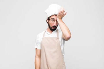 young crazy chef raising palm to forehead thinking oops, after making a stupid mistake or...