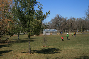 Fototapeta na wymiar Children Playing at the Park near a Greenhouse
