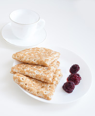 three pancakes for breakfast on a white plate with berries