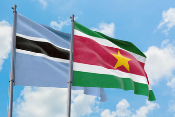 Suriname and Botswana flags waving in the wind against white cloudy blue sky together. Diplomacy concept, international relations.