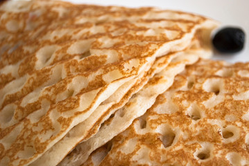pancakes with holes and berries close-up on a white plate