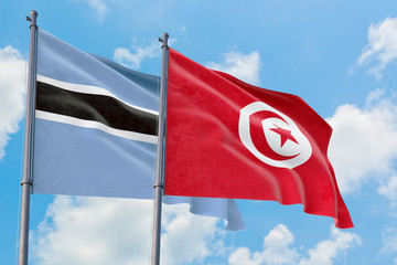 Tunisia and Botswana flags waving in the wind against white cloudy blue sky together. Diplomacy concept, international relations.