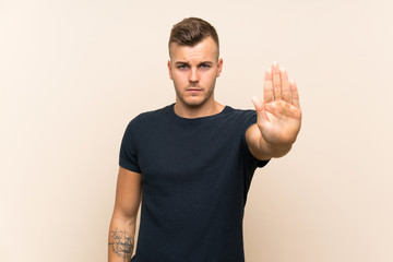 Naklejka premium Young handsome blonde man over isolated background making stop gesture