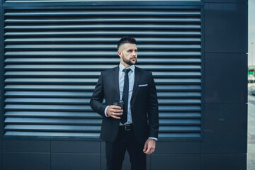 Bearded entrepreneur with beverage to go standing on street