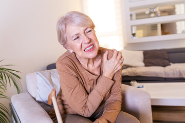 Elderly woman massaging the shoulder easing the aches. Joint pain concept. Senior old lady...