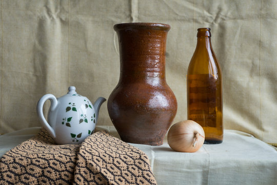 still life with a jug, an old bottle, a kettle and onions
