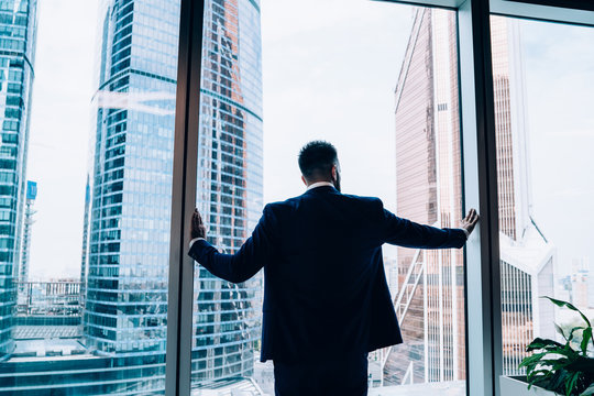 Smart Male Manager Looking At Cityscape From Window In Office