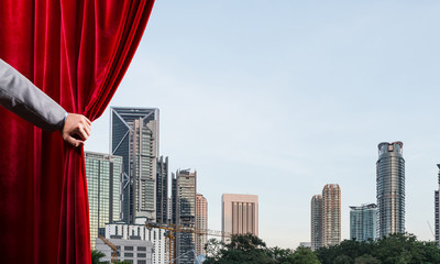Modern business cityscape behind curtain opened by businessman hand