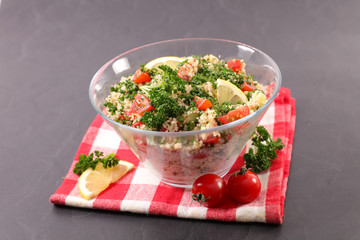 tabbouleh- semolina, tomato, cucumber and parsley on wood background